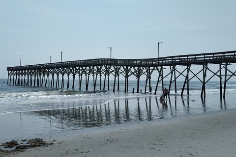A long wooden fishing pier reaching out over the surf at Holden Beach