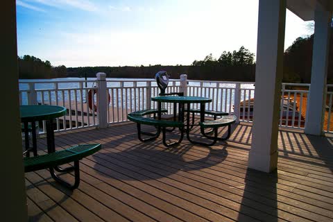 Picnic tables on a covered wooden deck overlooking Bass Lake