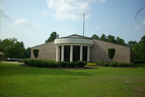 Hope Mills Town Hall, a low brick building with a white columned entrance behind a wide lawn