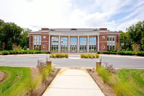 Brick town hall with a long walkway and landscaped lawn in Indian Trail