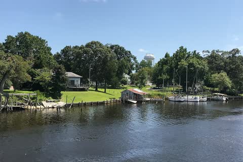 Tree-lined New River shoreline with small docks and boats in Jacksonville