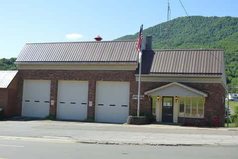 Brick Jefferson town hall and fire station with a wooded mountain behind