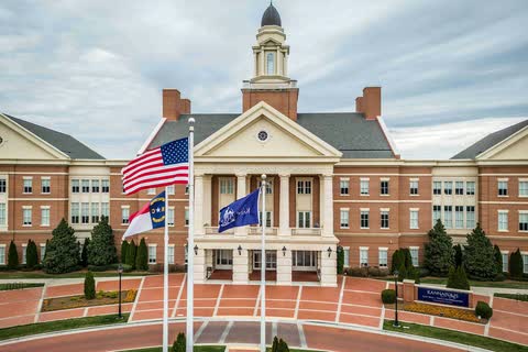 Red brick Kannapolis City Hall with a white clock cupola and flags in front