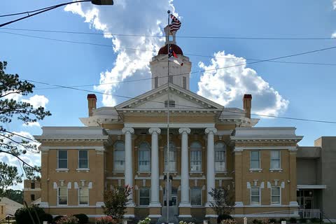 A tan-brick courthouse with tall white columns and a cupola in Kenansville