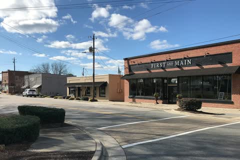 A brick commercial building and older storefronts at a downtown corner in Knightdale