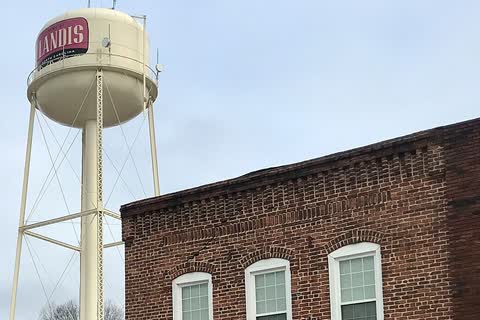 The Landis water tower rising above a two-story brick commercial building in downtown Landis