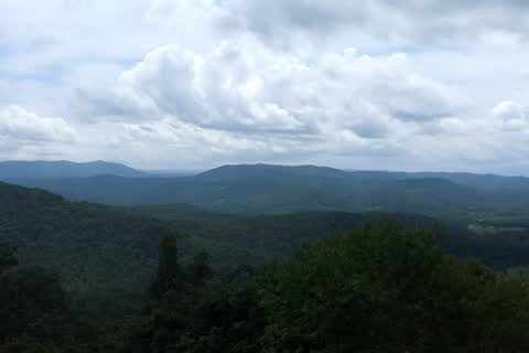 Wide view of forested mountain ridges under clouds from Jump Off Rock