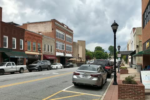 Brick storefronts, street lamps and parked cars on a downtown street in Lenoir