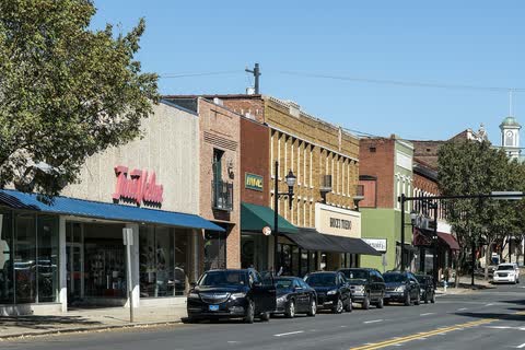 Brick storefronts and parked cars along South Main Street in Lexington, with a cupola rising at the end of the street