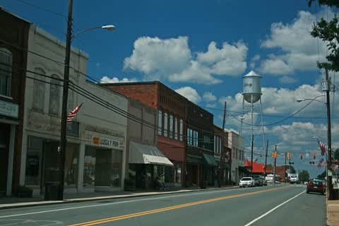 Main street of Liberty lined with brick storefronts under a blue sky, with the town water tower behind