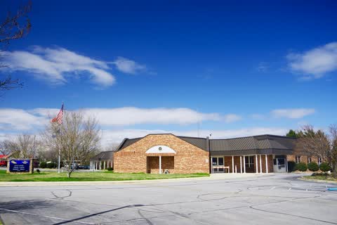 Low brick government center building with a flagpole and lawn in Long View