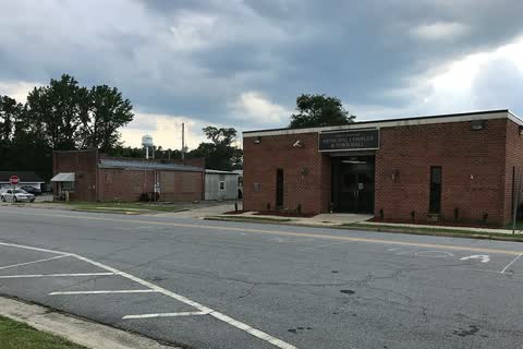 One-story brick buildings along a street in Macclesfield under a cloudy sky