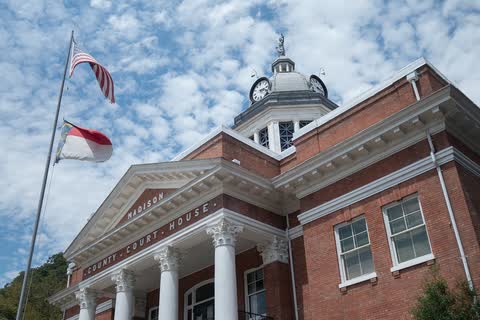 Brick Madison County Courthouse with white columns and a clock cupola in Marshall