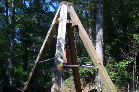 Tall wooden A-frame over a mine shaft among trees at Reed Gold Mine