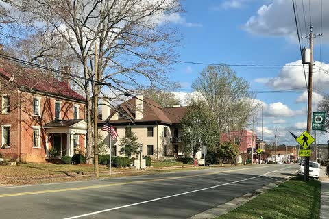 Historic brick buildings among bare trees along Broad Street in Milton
