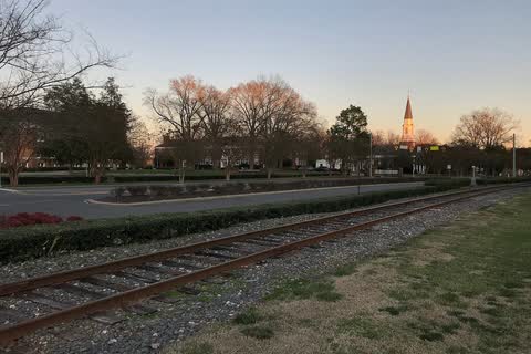 Railroad tracks in Misenheimer at dusk, with Pfeiffer University buildings and a spire on the skyline