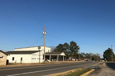 A white commercial building beside a two-lane road in Momeyer