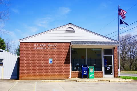 Brick Mooresboro post office with flags under a blue sky