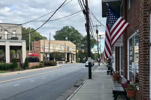 Downtown sidewalk in Mount Pleasant with an American flag and storefronts