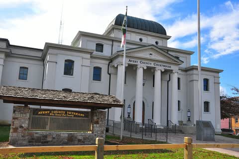 White Avery County Courthouse with columns and a dome in Newland