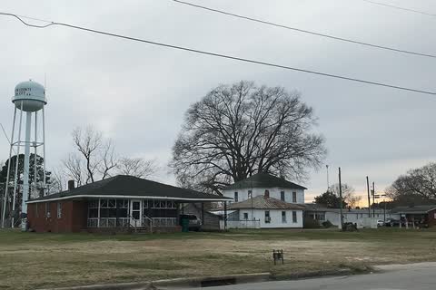 Houses and the town water tower across an open lot in Oak City