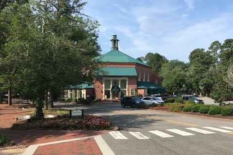Brick building with a green cupola beside a brick crosswalk in Pinehurst village