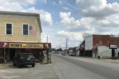 A two-story corner building and storefronts along a street in Pinetops