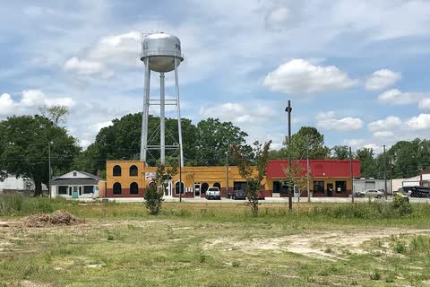 The Pink Hill water tower above a row of small shops beyond an open lot