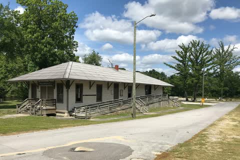 A long low wooden depot building beside a road in Pollocksville