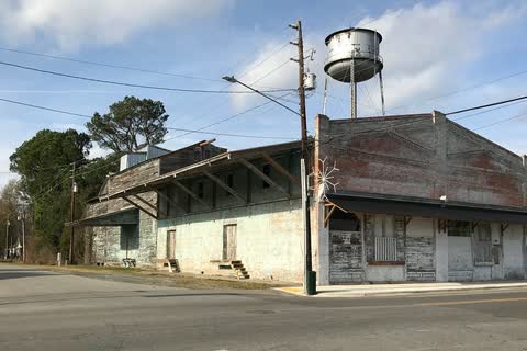 A weathered wooden mill building with the town water tower behind it in Princeton
