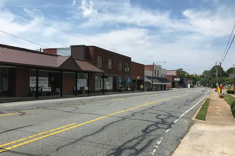 Row of low brick storefronts with covered sidewalks along a wide street in Randleman
