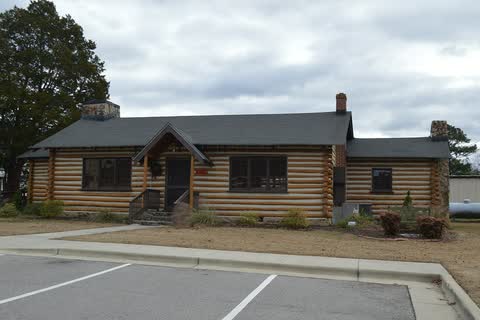 A log-style community house with a stone chimney in Red Oak