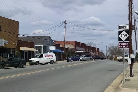 Downtown Robbins street with brick storefronts and a Highway 705 sign