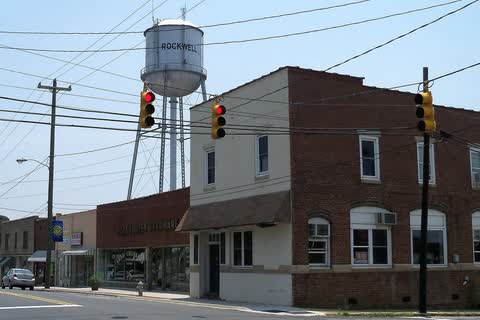 Brick commercial buildings at an intersection with the Rockwell water tower behind