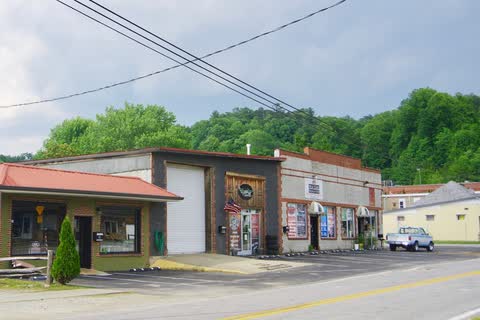 Low downtown shop buildings along US 178 in Rosman, with wooded hills behind