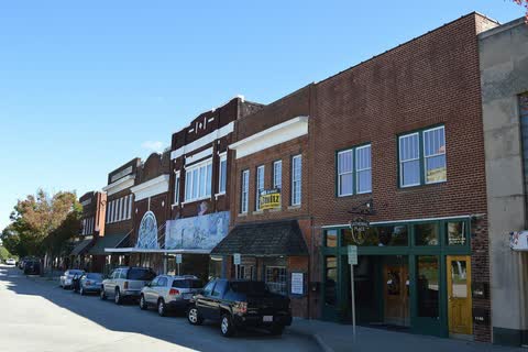 Row of brick storefronts with parked cars on Main Street in Roxboro