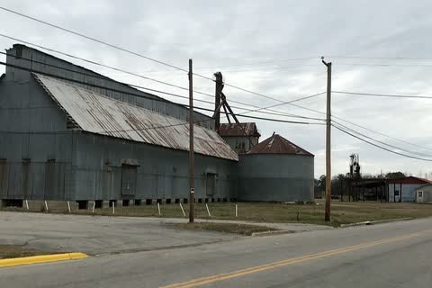 A large metal-sided agricultural building and the town water tower in Roxobel
