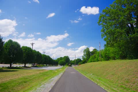 Paved Thermal Belt Rail Trail running between grassy banks and trees in Ruth