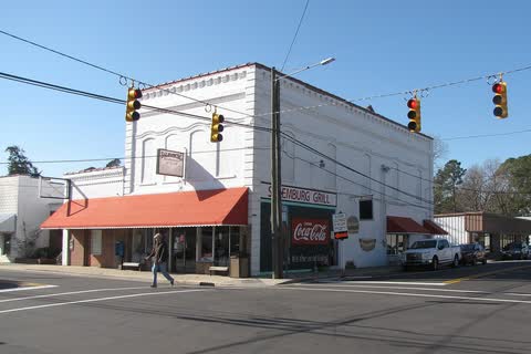 A white two-story corner commercial building at an intersection in Salemburg