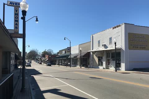 Sunny Main Street in Sanford with low brick storefronts and an old hardware store sign