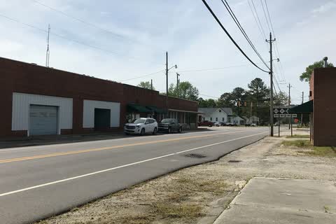A long low brick commercial building beside a two-lane road in Saratoga