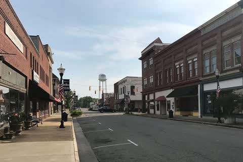 Two-story brick storefronts lining a downtown street in Selma, with the water tower in the distance