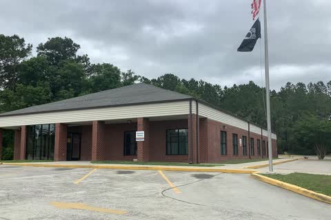 A brick post office building with a flagpole in Shallotte