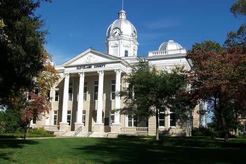 White neoclassical former courthouse with columns and a domed cupola in Shelby
