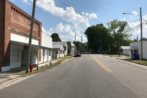 A brick storefront beside a two-lane street in Sims