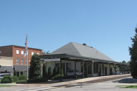 Railroad station with a long hipped roof beside the tracks in Southern Pines