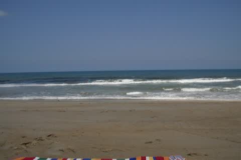 Waves breaking on a sandy beach at Southern Shores, with a striped towel in the foreground