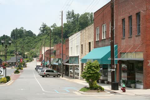 Downtown Spruce Pine street with brick shops, awnings and wooded hills behind