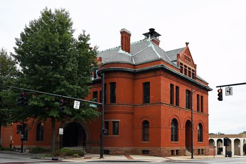 Red brick Romanesque-style city hall building at a street corner in Statesville