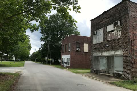 Two older brick commercial buildings beside a quiet street in Stedman